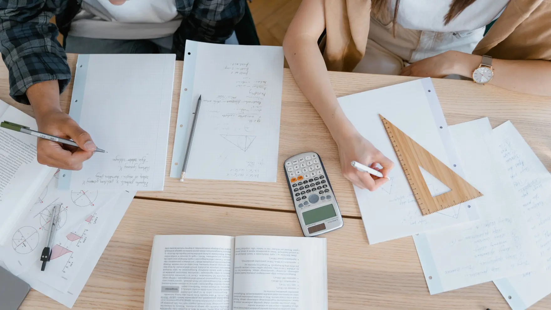 Masada matematik ödevi üzerinde çalışan öğrenciler, cetvel ve hesap makinesi