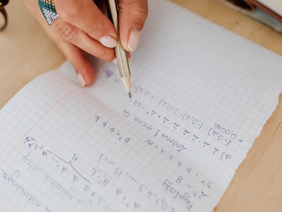 Kâğıt üzerine elle matematik işlemi yazan bir el